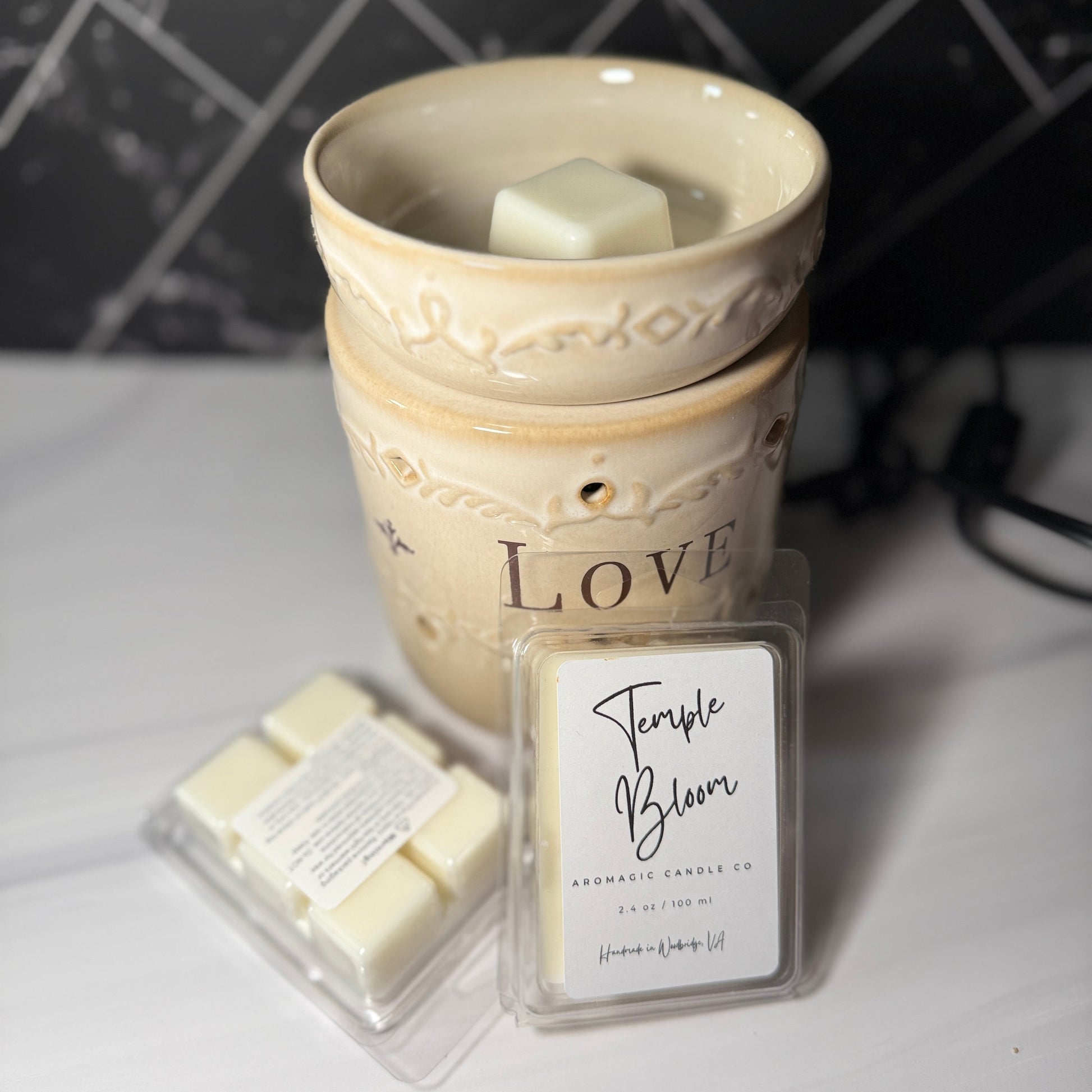 Wax warmer with wax melts and a label on a white surface with a tiled wall background