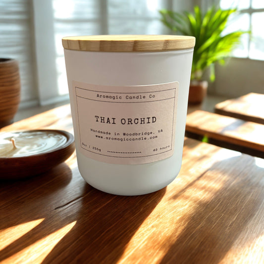 Candle labeled 'Thai Orchid' from Aromagic Candle Co on a wooden table with natural light.