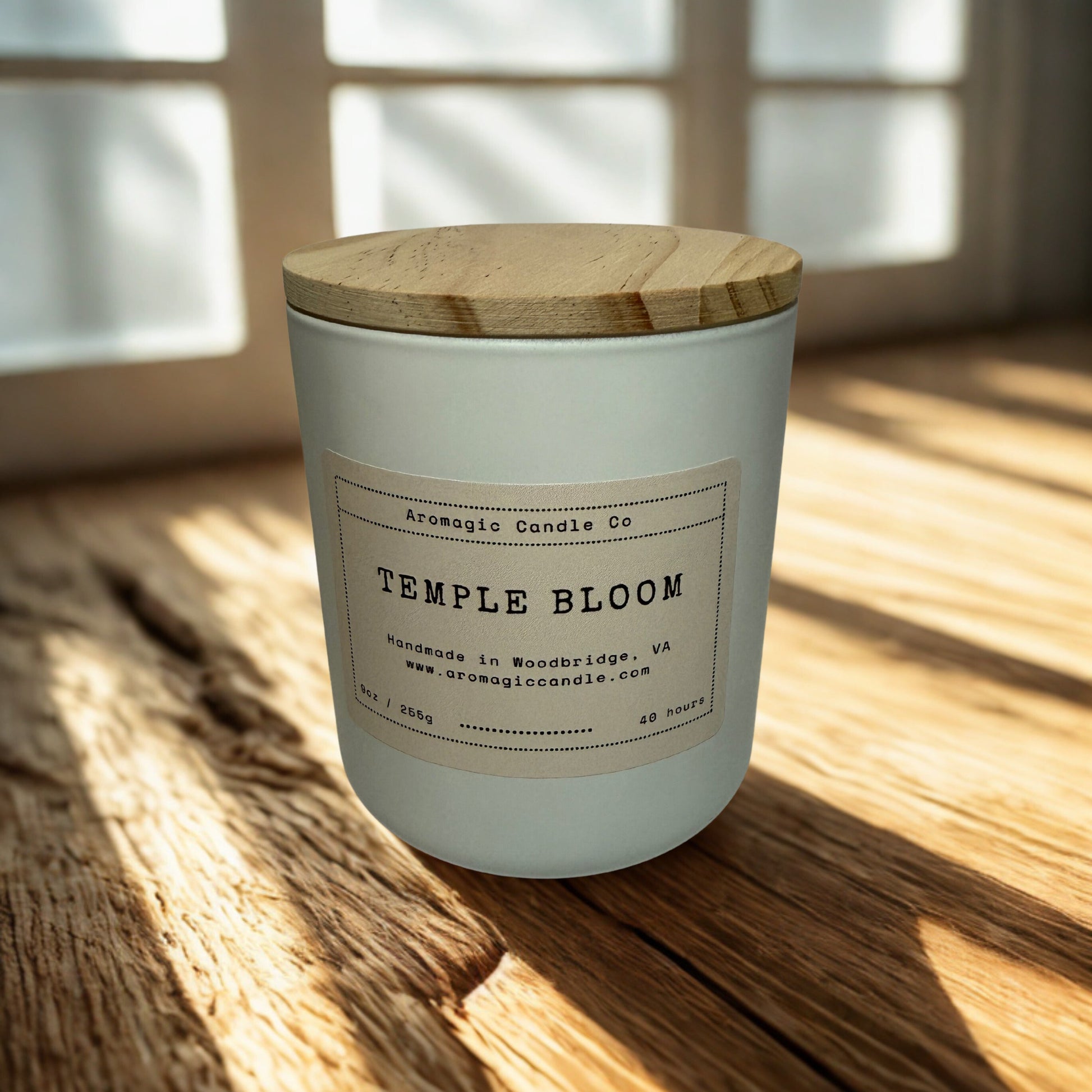 Candle labeled 'Temple Bloom' on a wooden surface with a window in the background