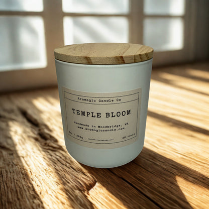 Candle labeled 'Temple Bloom' on a wooden surface with a window in the background
